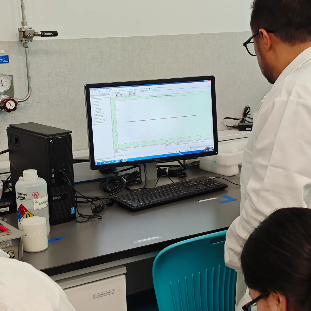 Especialista revisa datos en pantalla utilizando inteligencia artificial en laboratorios de análisis de materiales para mejorar procesos.